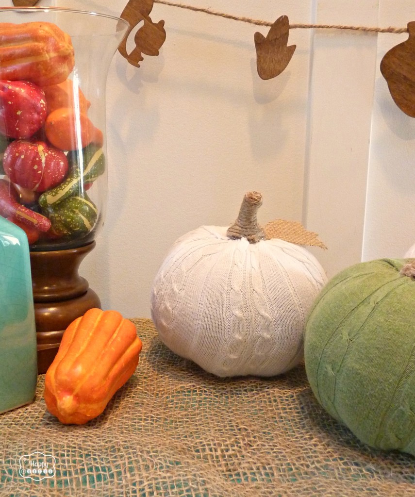There is an orange gourd beside the pumpkins.