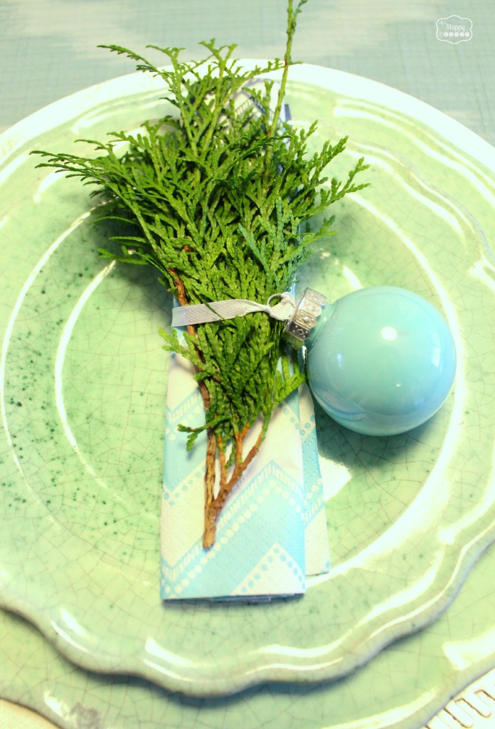 Cedar tree clippings with a Christmas ornament wrapped around it on the plate.