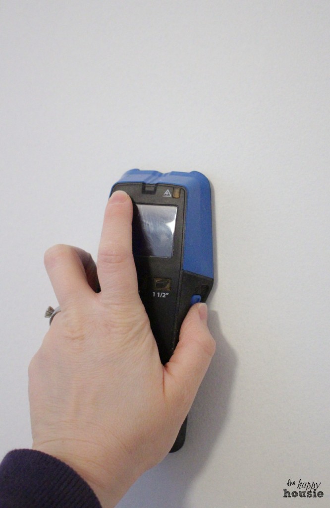 Using a stud finder on the wall.