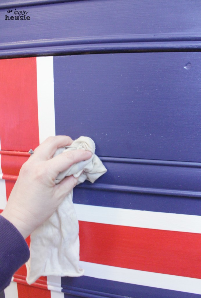 Applying wax to the dresser with a cloth.