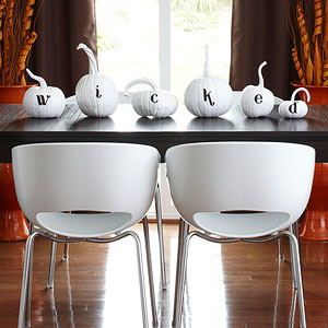 Wicked spelled out on white pumpkins displayed on a table as a centerpiece.