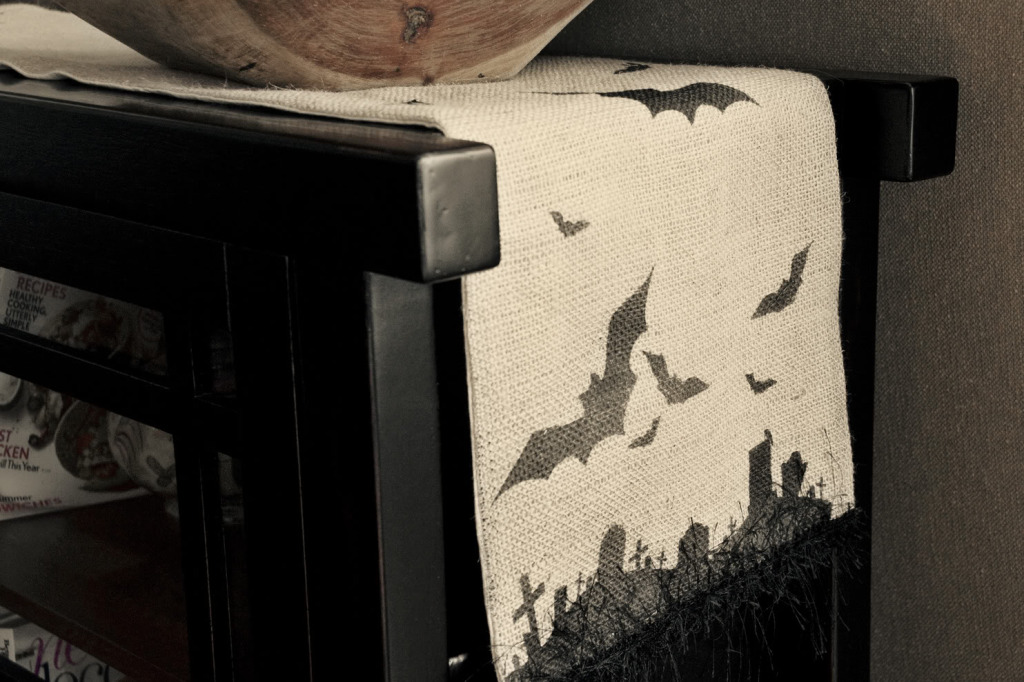 A burlap runner on a table that has bat imagery.