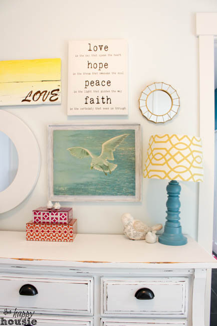 A picture of a seagull, a love and peace picture and a love picture with yellow above the dresser.