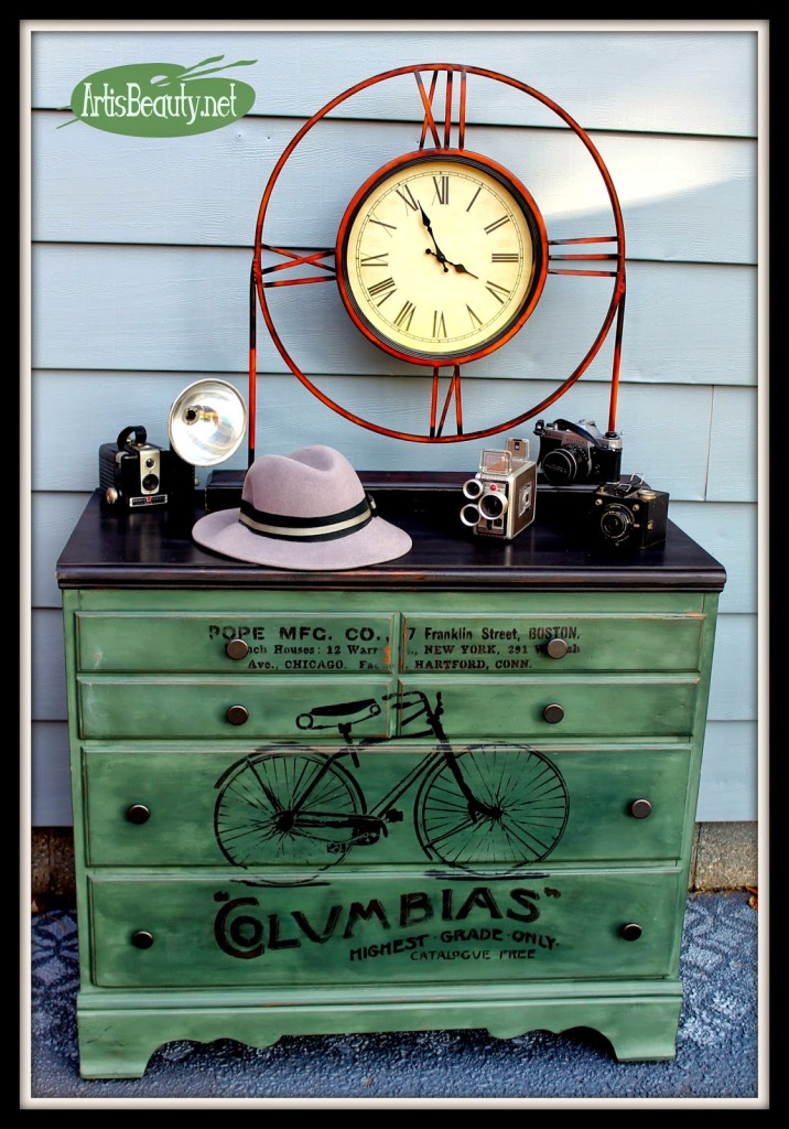 A dresser painted a distressed green and black bicycle and quotes on it.