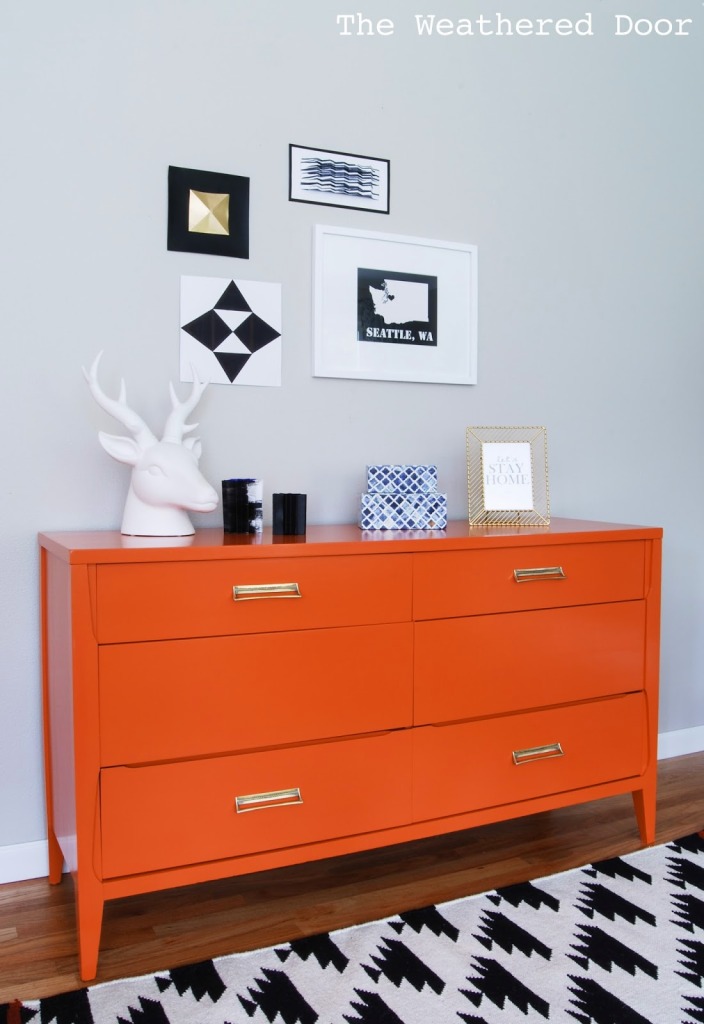 Persimmon dresser with a faux deer head on top and pictures on the wall above it.