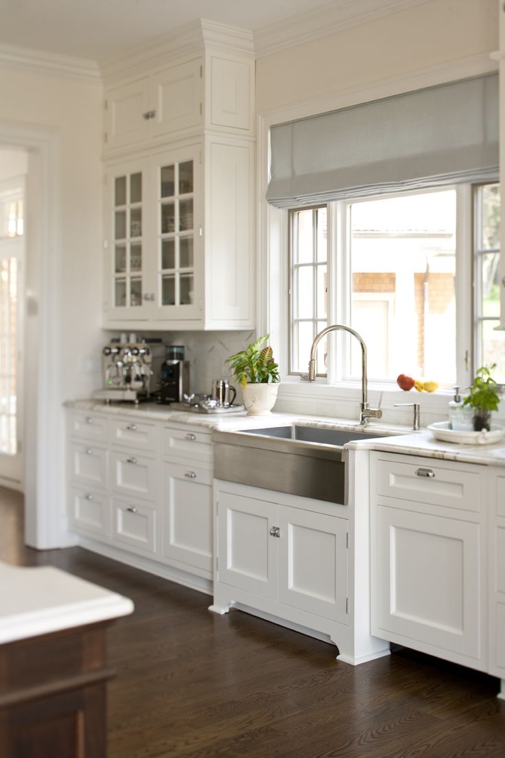 An all white kitchen with a stainless steel sink.