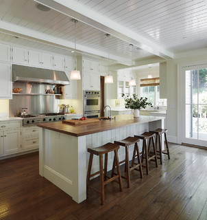 Wooden stools are lined up in this white kitchen.