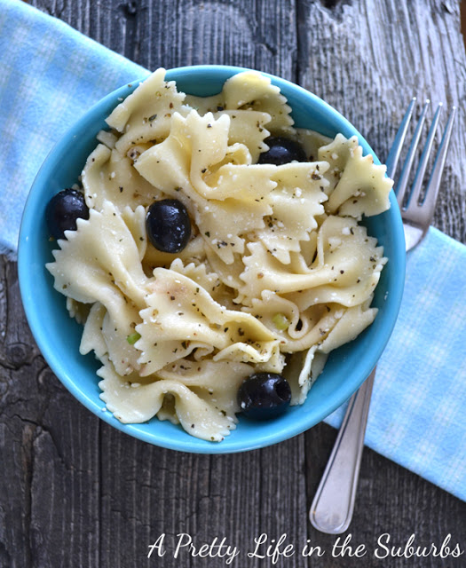 Bow pasta with olives on the table beside a fork.